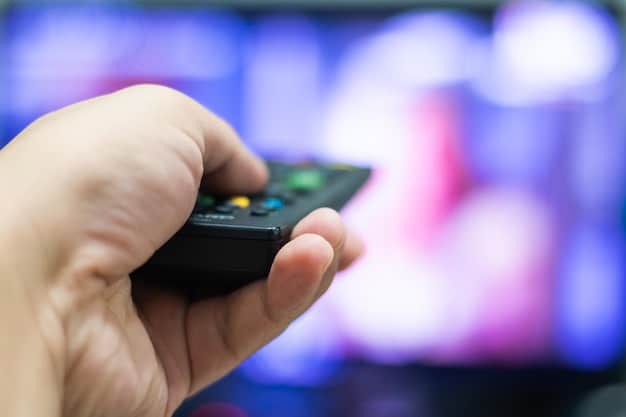 A hand using a remote control with multiple streaming service logos displayed on the screen. The logos are partially blurred, except for a few that are highlighted.