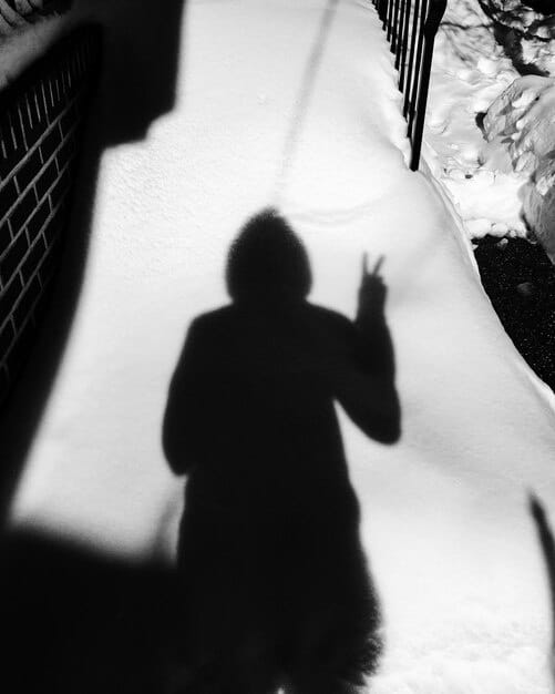 A blurred image of a mysterious figure lurking in the shadows. The focus is on creating a sense of intrigue and uncertainty.