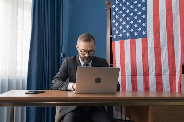 A medium shot of John Dutton sitting at his desk in the governor's office, looking weary and burdened. The American flag is visible in the background.